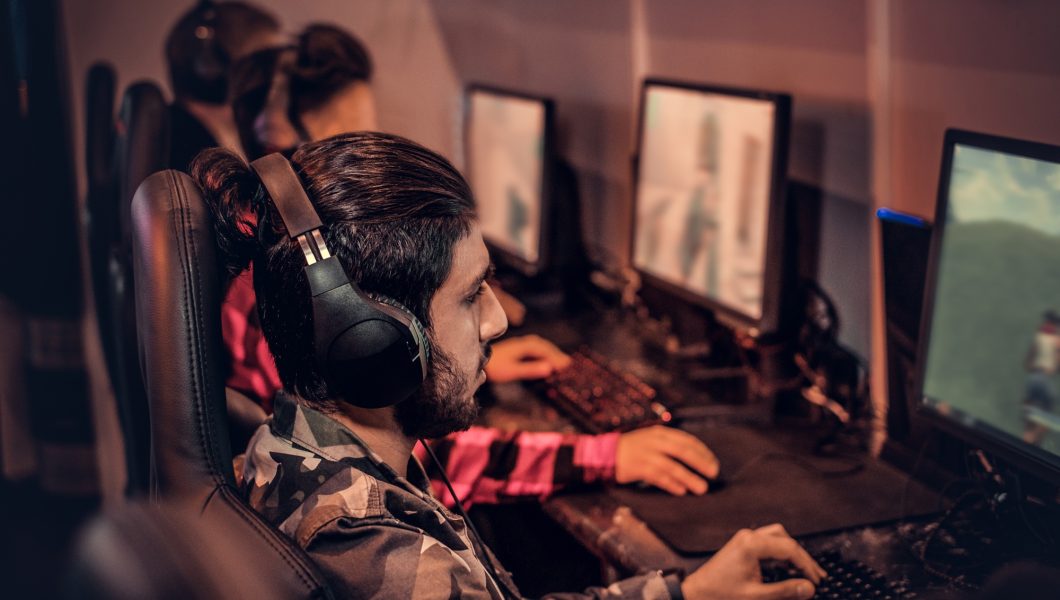 Team of teenage gamers plays in a multiplayer video game on pc in a gaming club.